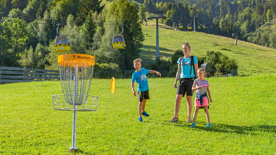 Mutter mit Kindern vor Disc-Golf Korb